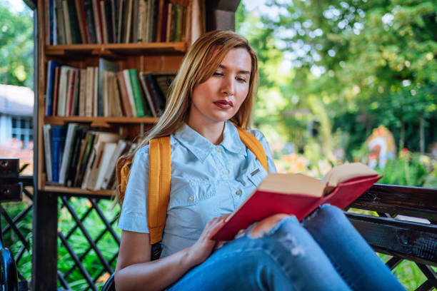 istock Woman reading a book in the open library 1273715150