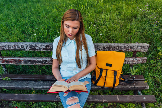 istock Woman reading a book in the park 1273715451