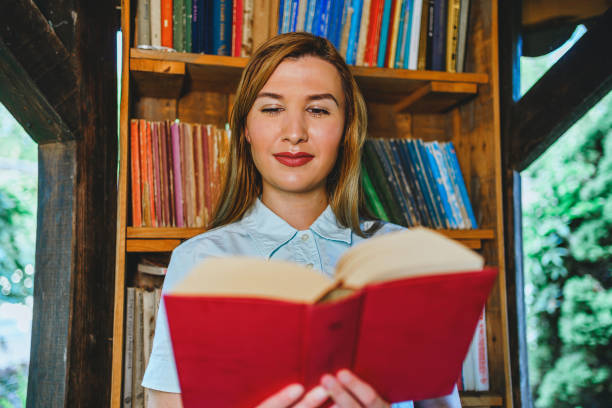 istock Woman reading a book in the open library 1273716248