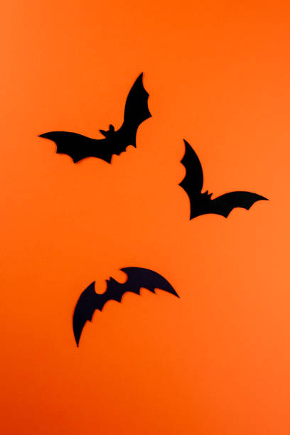 istock Three black paper bats on orange background 1273717727