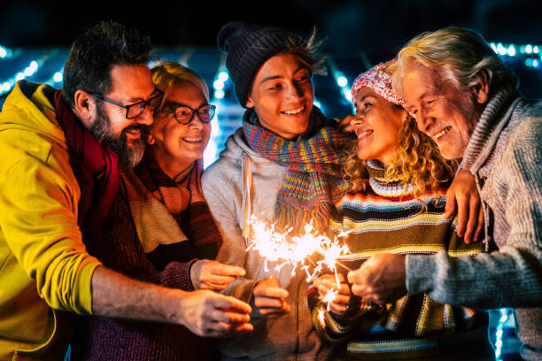 família feliz caucasiana desfrutar e celebrar à noite com brilho de fogo todos juntos se divertindo - celebração de natal e véspera de ano novo para grupo de pessoas alegres misturadas idades e gerações - group of objects travel friendship women - fotografias e filmes do acervo