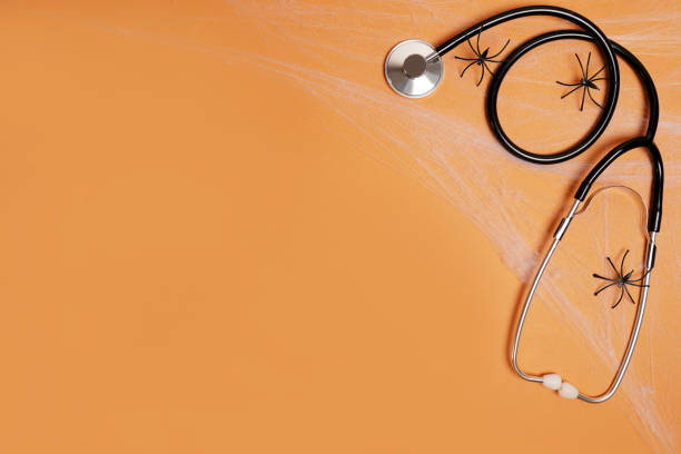 istock Halloween decor spiders and stethoscope on orange background with copy space. Medical Halloween in the hospital 1273723145