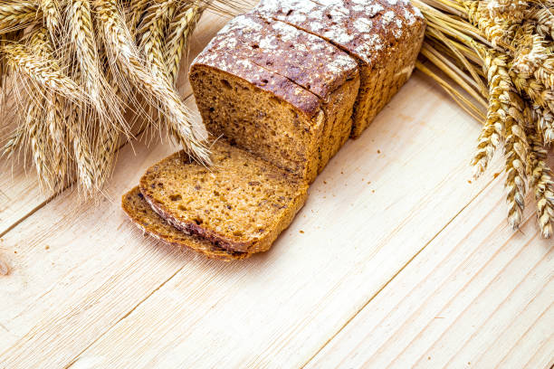istock Freshly baked bread. Fresh loaf of rustic traditional bread with wheat grain ear or spike plant on wooden texture background. Rye bakery with crusty loaves and crumbs. Healthy Food concept. 1273724849