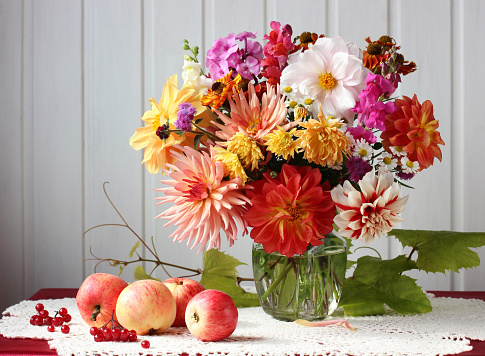 bouquet of garden flowers, apples and viburnum on the table. autumn bright still life, rustic interior.