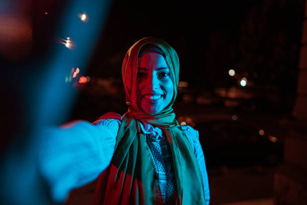 Young muslim woman taking selfie outdoors at night Beautiful smiling muslim woman taking selfie in city at night hijab photos stock pictures, royalty-free photos & images