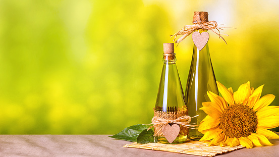 Rural still-life - sunflower oil in bottles with flowers of sunflower (Helianthus annuus), closeup with space for text