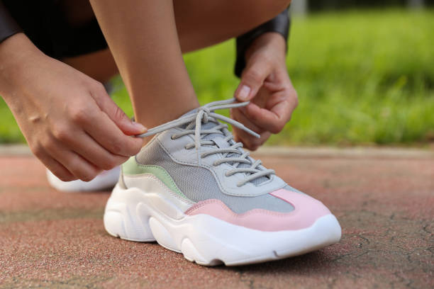 istock woman tying shoelaces on her sneakers 1273749116
