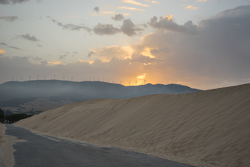 Road with dunes. Windmills on a mountain at dawn.