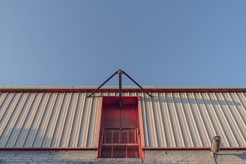 Second floor goods entrance and winch of a warehouse against a clear sky at sunset.  Belfast, Northern Ireland.