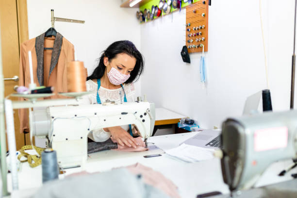 istock Seamstress adjusting the textile on sewing machine after she checked right measures on her laptop 1273759645