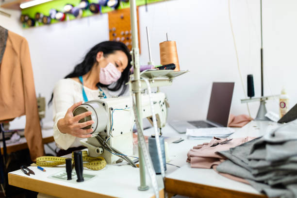 istock Seamstress adjucting sewing machine her desing studio while working during COVID-19 pandemic 1273759662