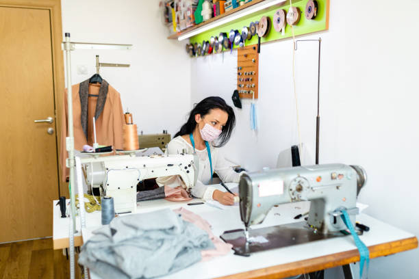 istock Responsible female tailor wearing protective face mask while working on a new clothing line design on her laptop 1273759686