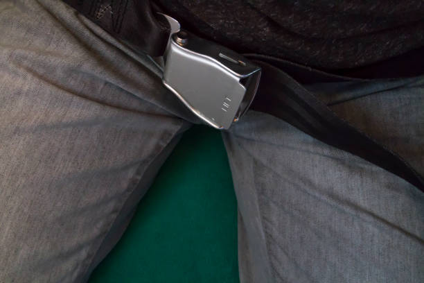Close-up view of man using airplane seatbelt during a fly inside the aircraft in airplane. Safety concept.