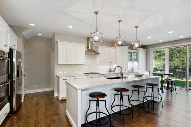 New white kitchen with brow natural wood flooring Pendant lights hang above kitchen island in open floor plan bar stool photos stock pictures, royalty-free photos & images
