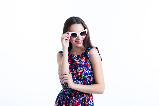 Portrait of cute summer brunette woman in sunglasses and colorful dress, isolated on white.