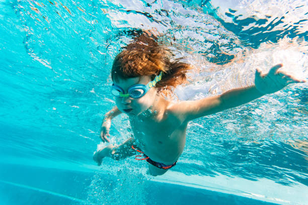 istock Little boy swimming underwater in pool 1273763414
