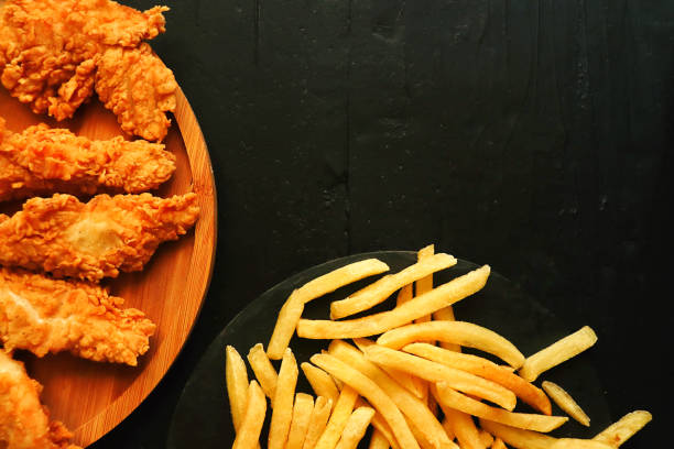 Fast food: chicken strips and fries top view on black background