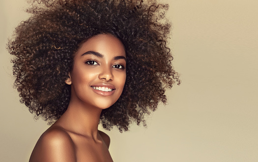 Wide toothy smile and expression of happiness on the face of young brown skinned woman. Natural, dense afro hair on the head of young beautiful model.Girl with vibrant, melanin-rich skin tone.
