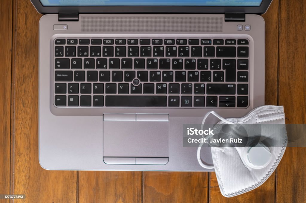 notebook keyboard seen from above on a wooden desk with a white FPP2 KN95 mask laptop keyboard seen from above on a wooden desk with a white FPP2 KN95 mask Machine Valve Stock Photo