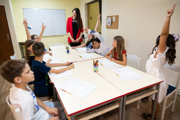 istock Group of elementary students raising their hands to answer the teacher's question 1273774625