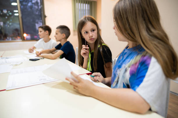 istock Two young girls talking in the class about the school paperwork 1273774631