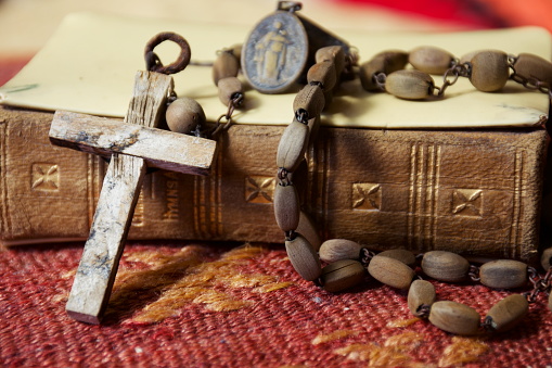 Close-Up of Old Aged Vintage Wooden Rosary Prayer Beads with an Antique Bible Background.