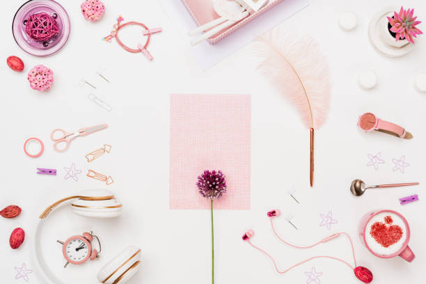 Creative woman home office desk workspace mockup with grid paper, pink flower, feathered pen, working accessories, coffee cup, flowerpot. Flat lay, top view. Stylish fashion female concept