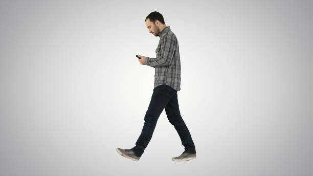 istock Young smart casual man walking and reading message on cell phone 1273788180