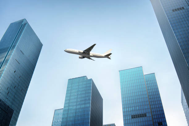 istock low angle view of plane fly over modern office buildings. 1273788836