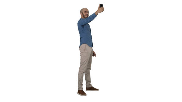 Selfie time! Handsome young man taking selfie with his phone on white background