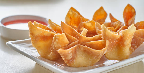 chinese crab rangoon fried wontons on plate with red sauce stock photo