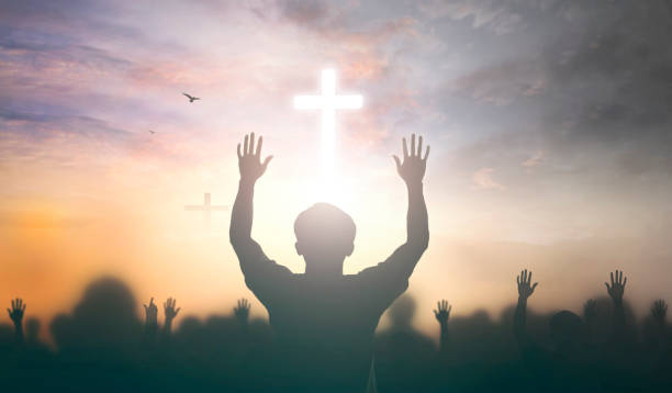 концепция поклонения: христианские люди поднимают руку над крестом на духовном фоне неба - surrendering стоковые фото и изображения