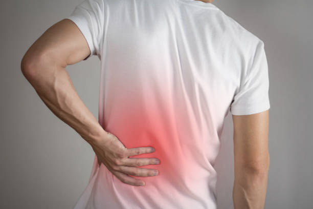 Lower back pain in a man. Highlighted in red. On a gray background. Close up Lower back pain in a man. Highlighted in red. On a gray background. Close up. painfully stock pictures, royalty-free photos & images