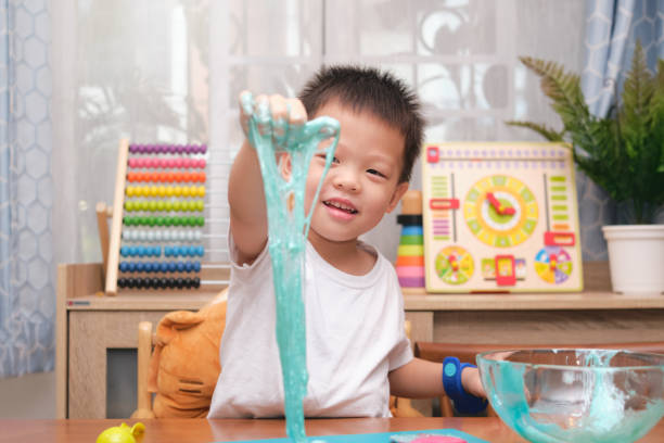 Cute  Asian 4 years old boy having fun making fluffy slime, Young kid having fun playing and being creative by science experiment homemade toy called Slime