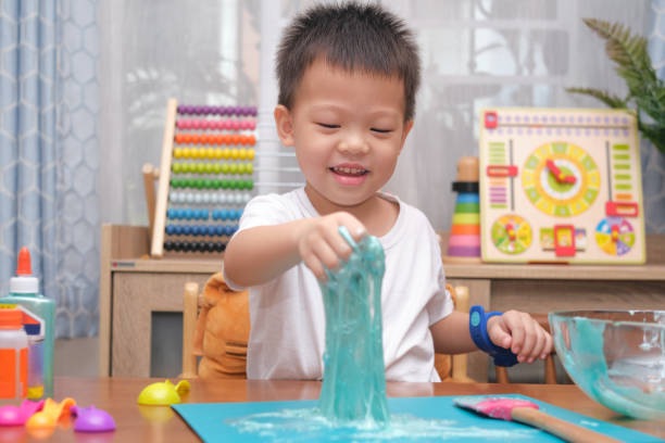 istock Cute  Asian 4 years old boy having fun making fluffy slime, Young kid having fun playing and being creative by science experiment homemade toy called Slime 1273805582