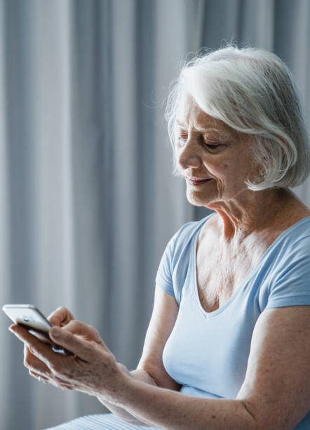 istock Smiling senior woman using mobile phone in bedroom 1273811418