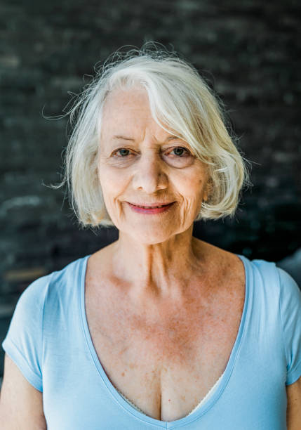 Smiling wrinkled woman sitting in bedroom Portrait of smiling wrinkled female with short hair. Elderly woman is sitting comfortably in bedroom. She is wearing casuals. cleavage stock pictures, royalty-free photos & images