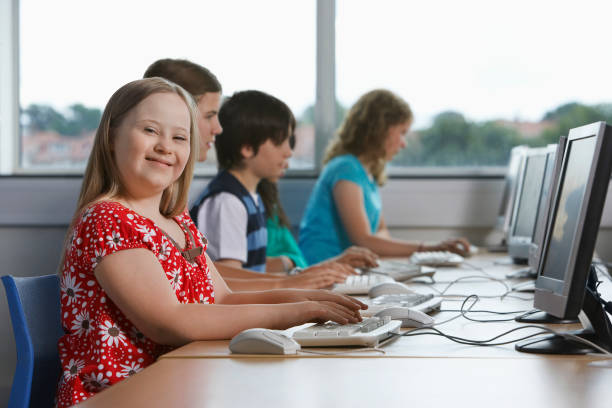 14260012 Portrait of girl (10-12) with Down syndrome in computer lab children in background 12 13 years pre adolescent child female blond hair stock pictures, royalty-free photos & images