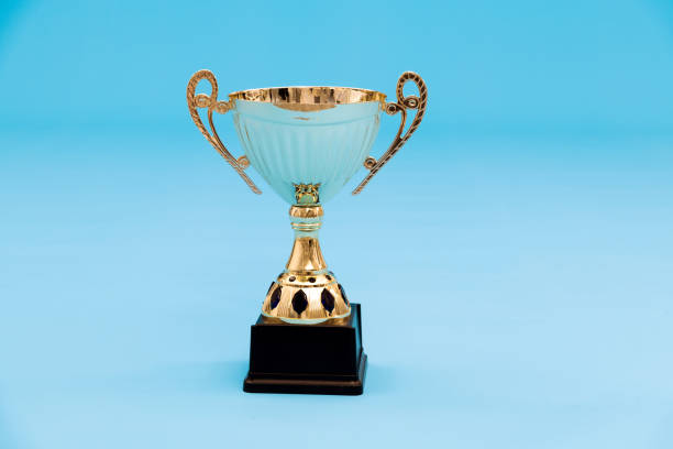 golden trophy on blue background - effort gold indoors studio shot imagens e fotografias de stock