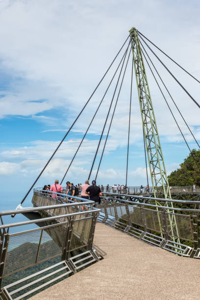 les touristes visitent le pont de ciel sur la montagne dans le fond de la mer et l’île de langkawi, malaisie - tropical rainforest elevated walkway pulau langkawi malaysia photos et images de collection