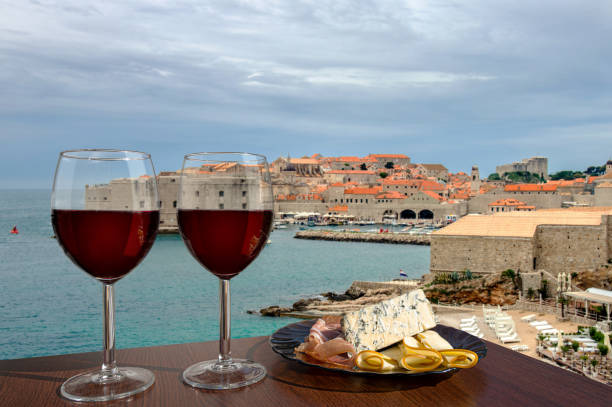 두브로브니크 도심 배경에 대한 샤르큐테리 구색과 와인 두 잔. 휴가 개념. 크로아티아 두브로브니크의 유서 깊은 중심지의 해변과 도심 - wine port 뉴스 사진 이미지