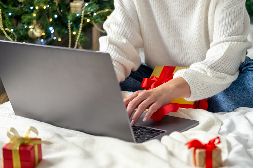 Christmas online shopping. girl makes order on laptop. Woman buy presents, prepare to xmas, among gift boxes and packages. Winter holidays sales