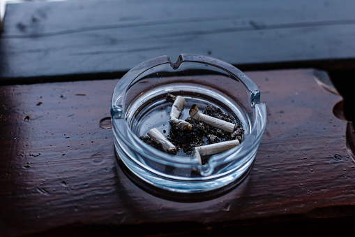 Closeup view of ashtray full of cigarette butts on the table