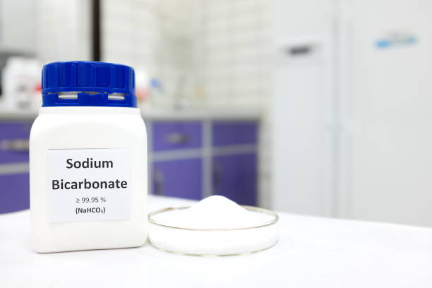 Selective focus of a bottle of sodium bicarbonate chemical compound or baking soda beside a petri dish with solid crystalline powder substance. White Chemistry laboratory background with copy space. Selective focus of a bottle of sodium bicarbonate chemical compound or baking soda beside a petri dish with solid crystalline powder substance. White Chemistry laboratory background with copy space. sodium stock pictures, royalty-free photos & images