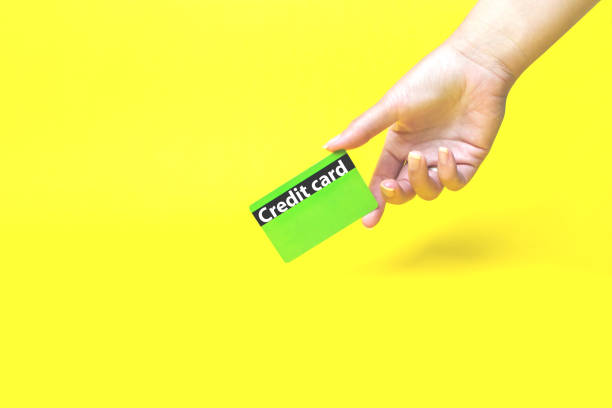 istock Hand holds a Bank card on yellow background. 1273823556