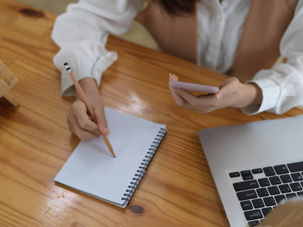 istock Female student looking for an idea on smartphone and write it down in notebook 1273824390