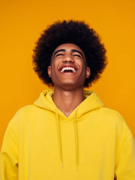 孤立��した黄色の背景の上に立ってパーカーを着たアフリカの髪型を持つアフリカ系アメリカ人男性 - men laughing african descent color image ストックフォトと画像