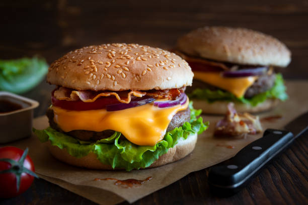 istock Burger with cheese, bacon, tomato and lettuce on dark wooden background 1273824429