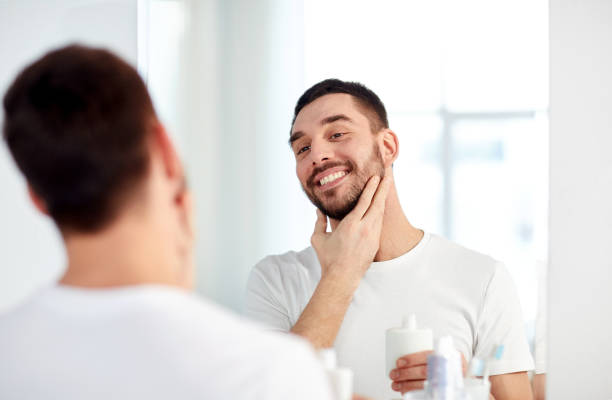 istock happy man applying aftershave at bathroom mirror 1273824482