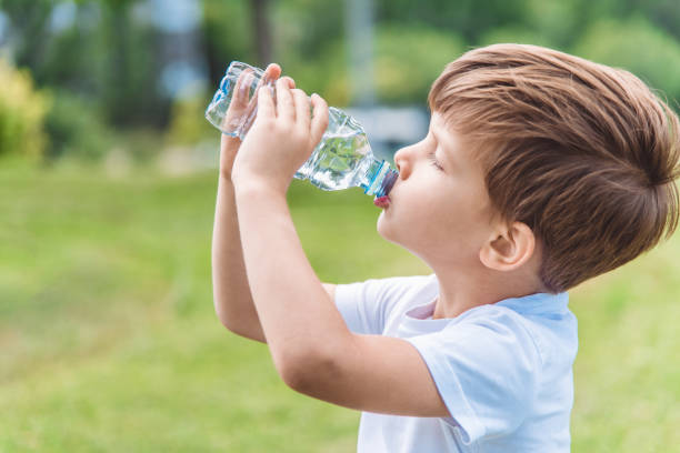 istock Cute child drinks water from a bottle on the street in summer 1273824533